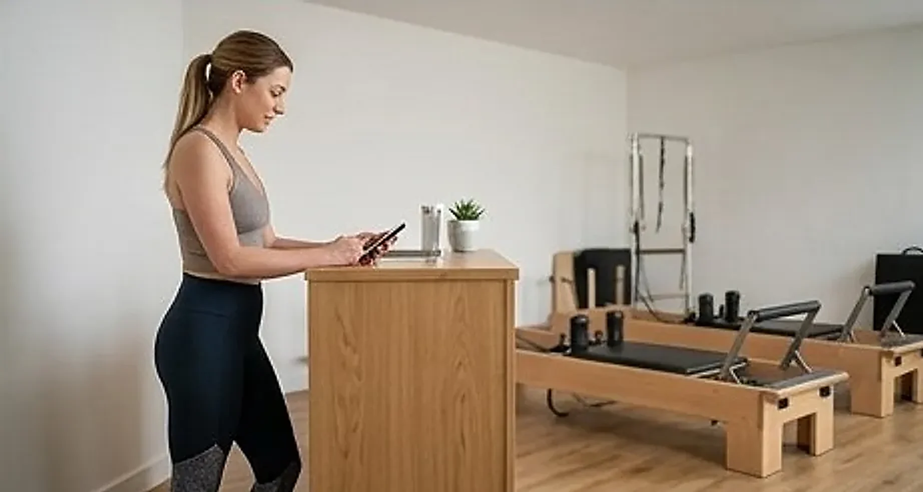 Studio owner checking a class enquiry at the front desk of a reformer studio